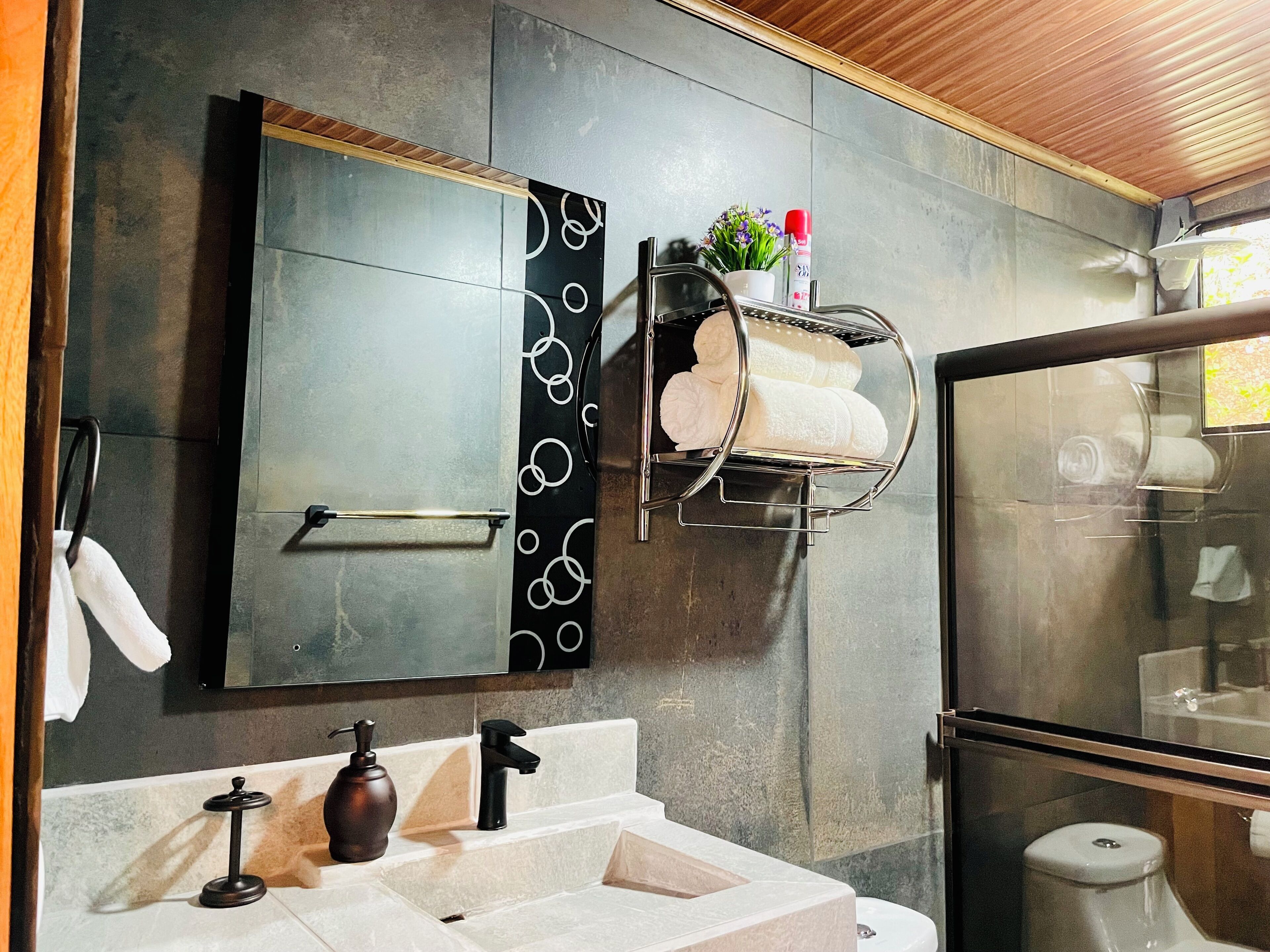 A modern bathroom with a large mirror, a towel rack, a sink, and a toilet.