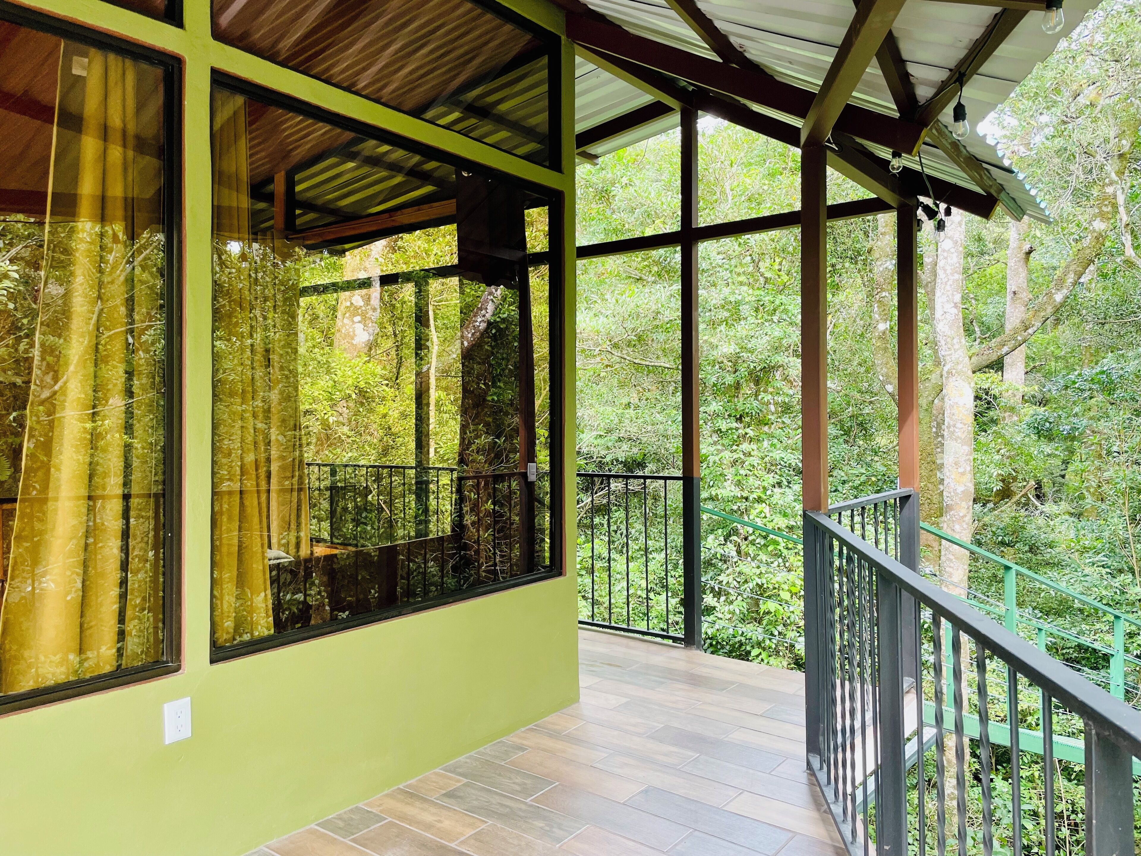 A covered balcony with a view of dense greenery.