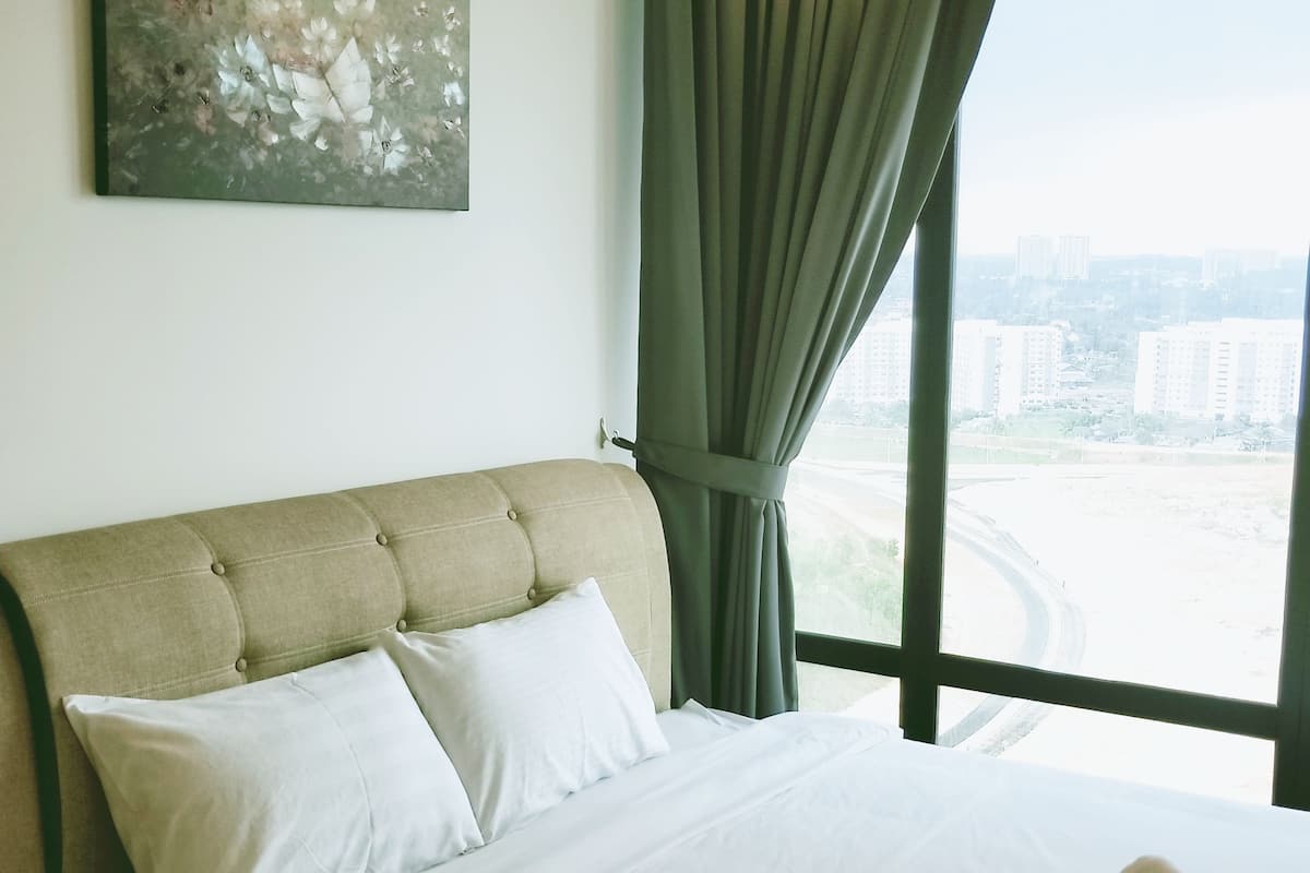 A hotel room with a large bed, a view of the city through the window, and a painting on the wall.