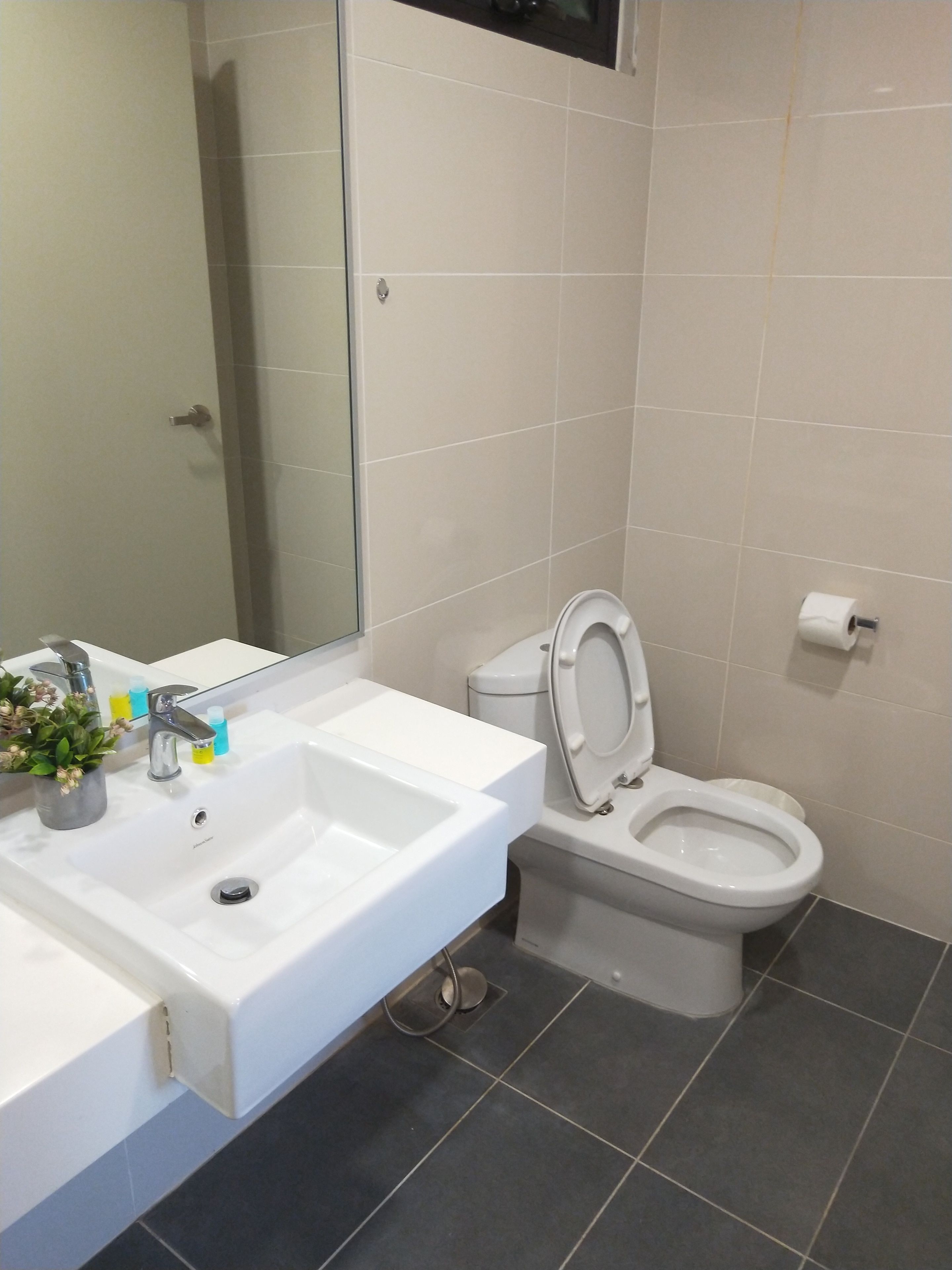 Baño con lavamanos, espejo y retrete blanco.