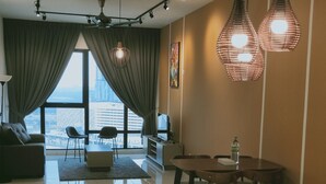 A modern living room with a large window, a sofa, a dining table with chairs, and a ceiling fan. - South Key Mosaic (Johor Bahru)