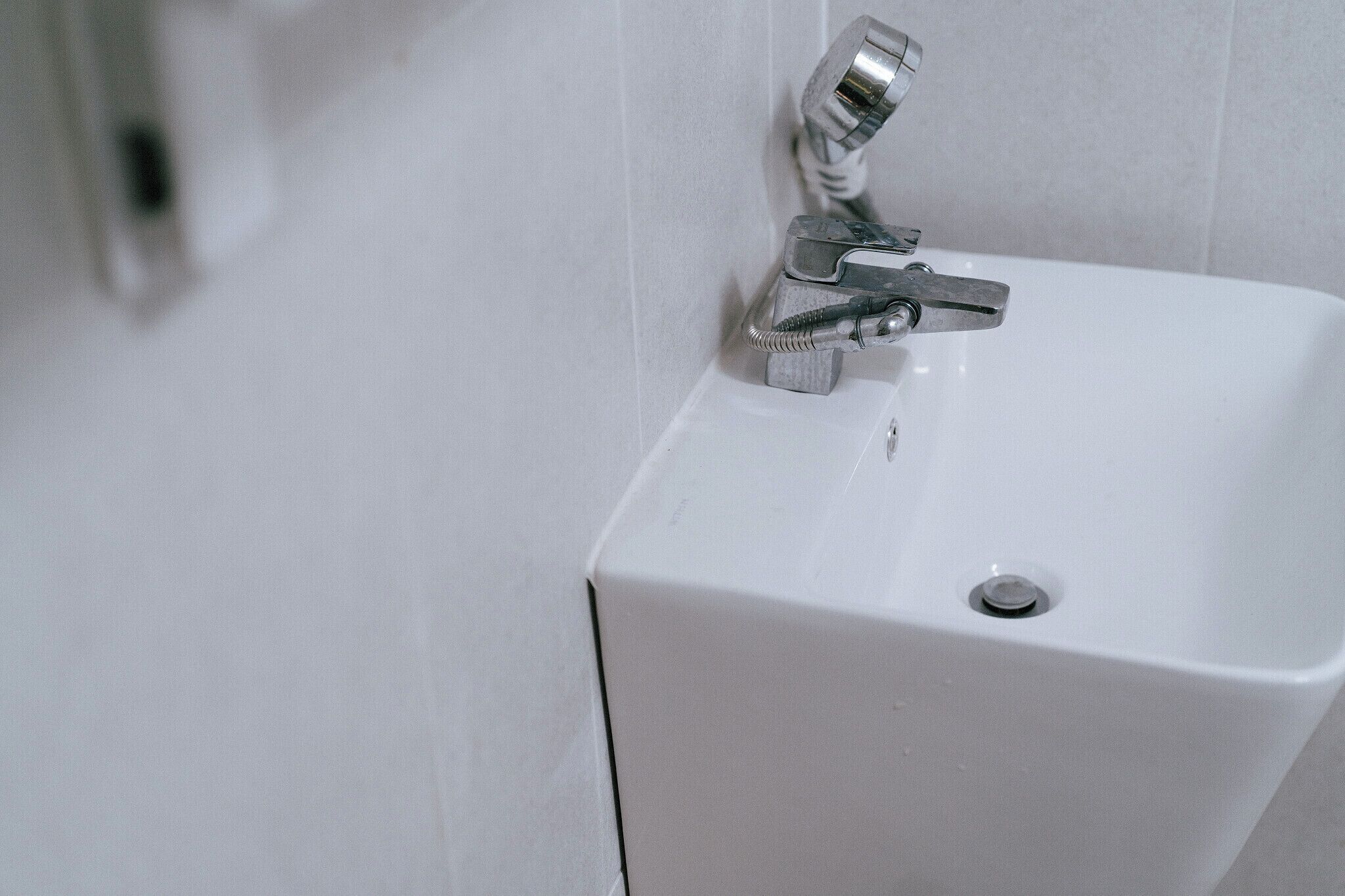 A white bathroom sink with a chrome faucet and a drain.