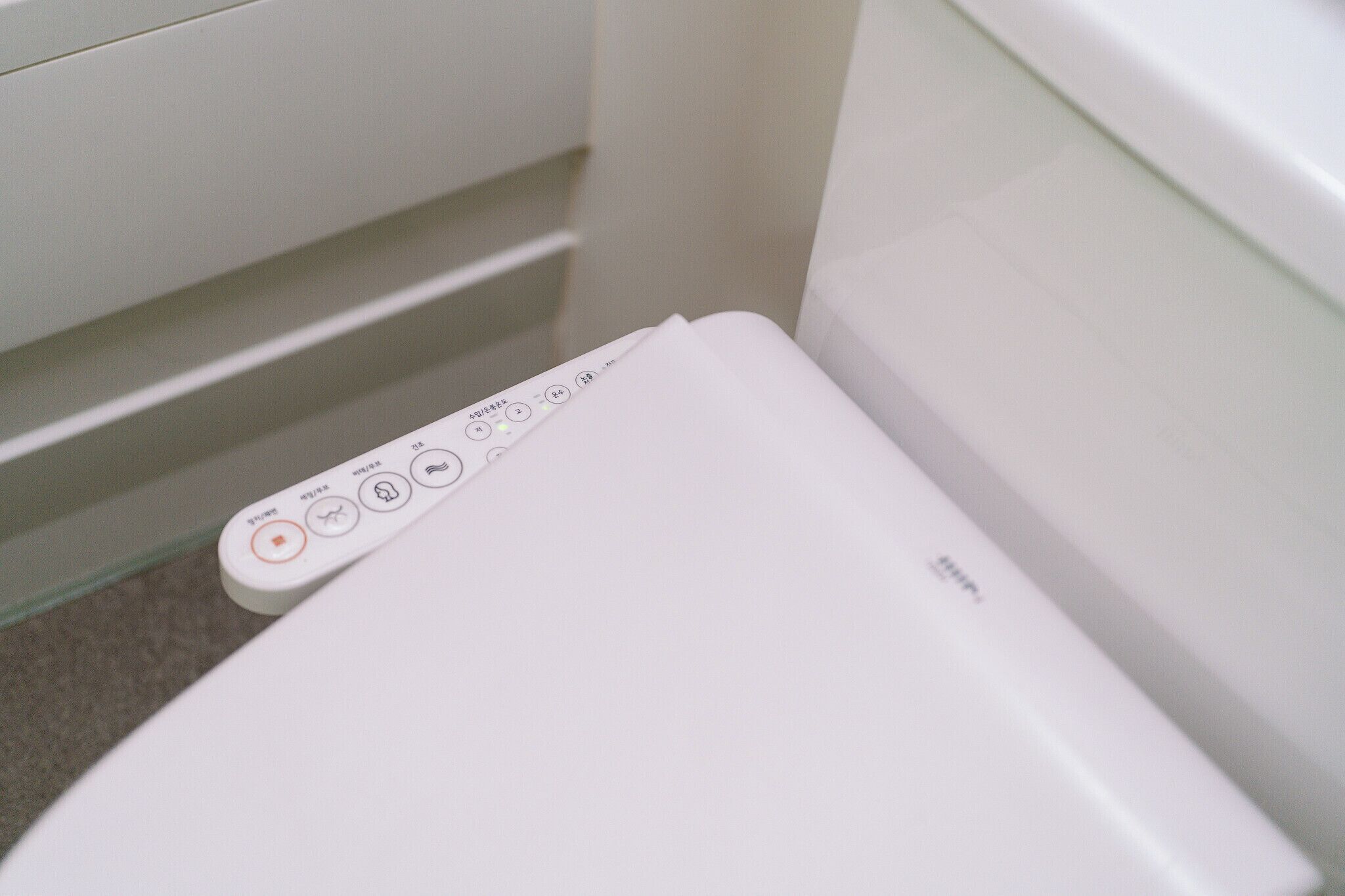 Een wit toilet met bedieningspaneel, inclusief knoppen en een display.