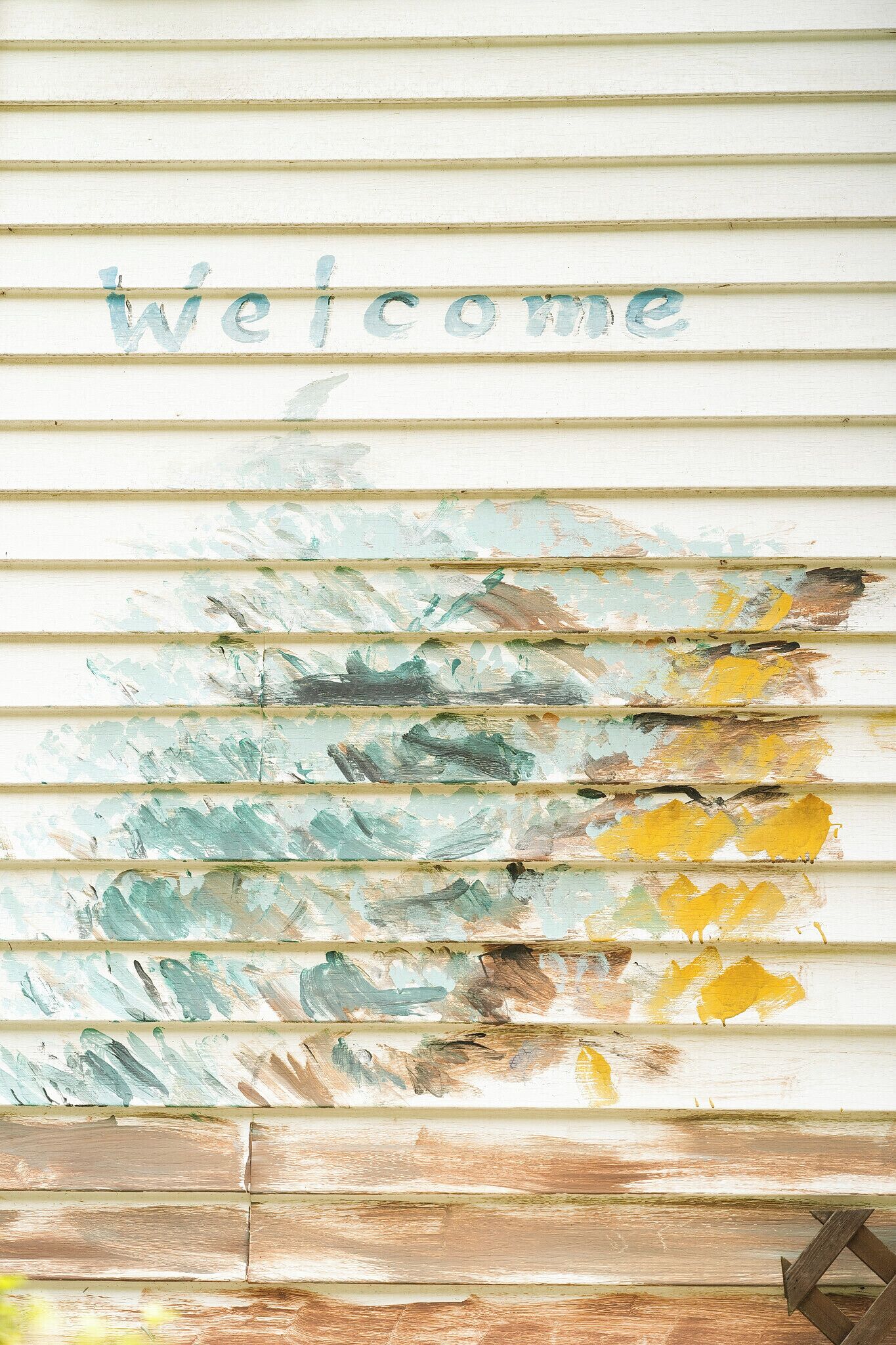 A wall with horizontal wooden slats and the word 'Welcome' painted in a distressed style.