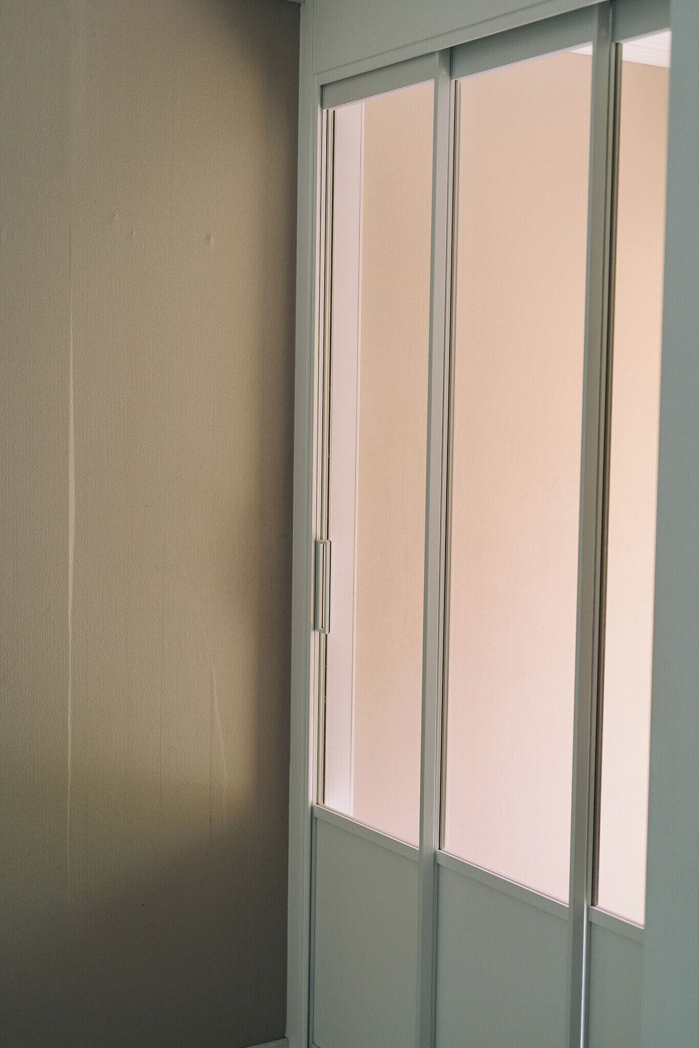Um quarto com uma porta de correr, uma parede simples e uma janela.