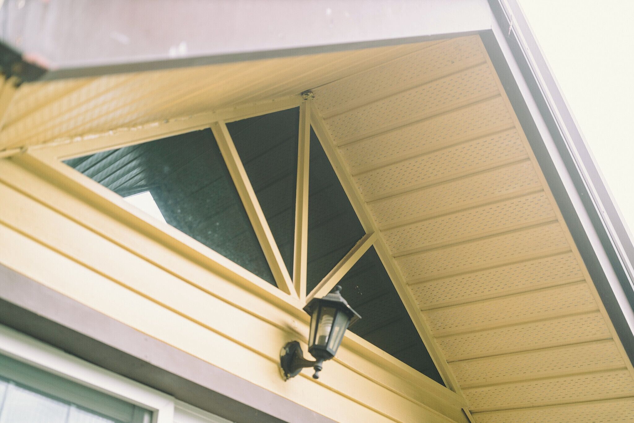 A building's exterior with a yellow awning, a black lantern, and a window.