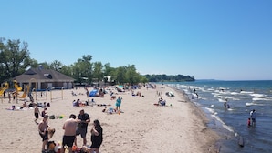 Une plage avec une aire de jeux, des gens qui prennent un bain de soleil et un ciel dégagé.