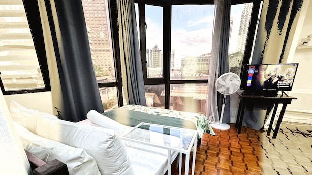 Et værelse med en seng, et lille bord, en ventilator og et fjernsyn.