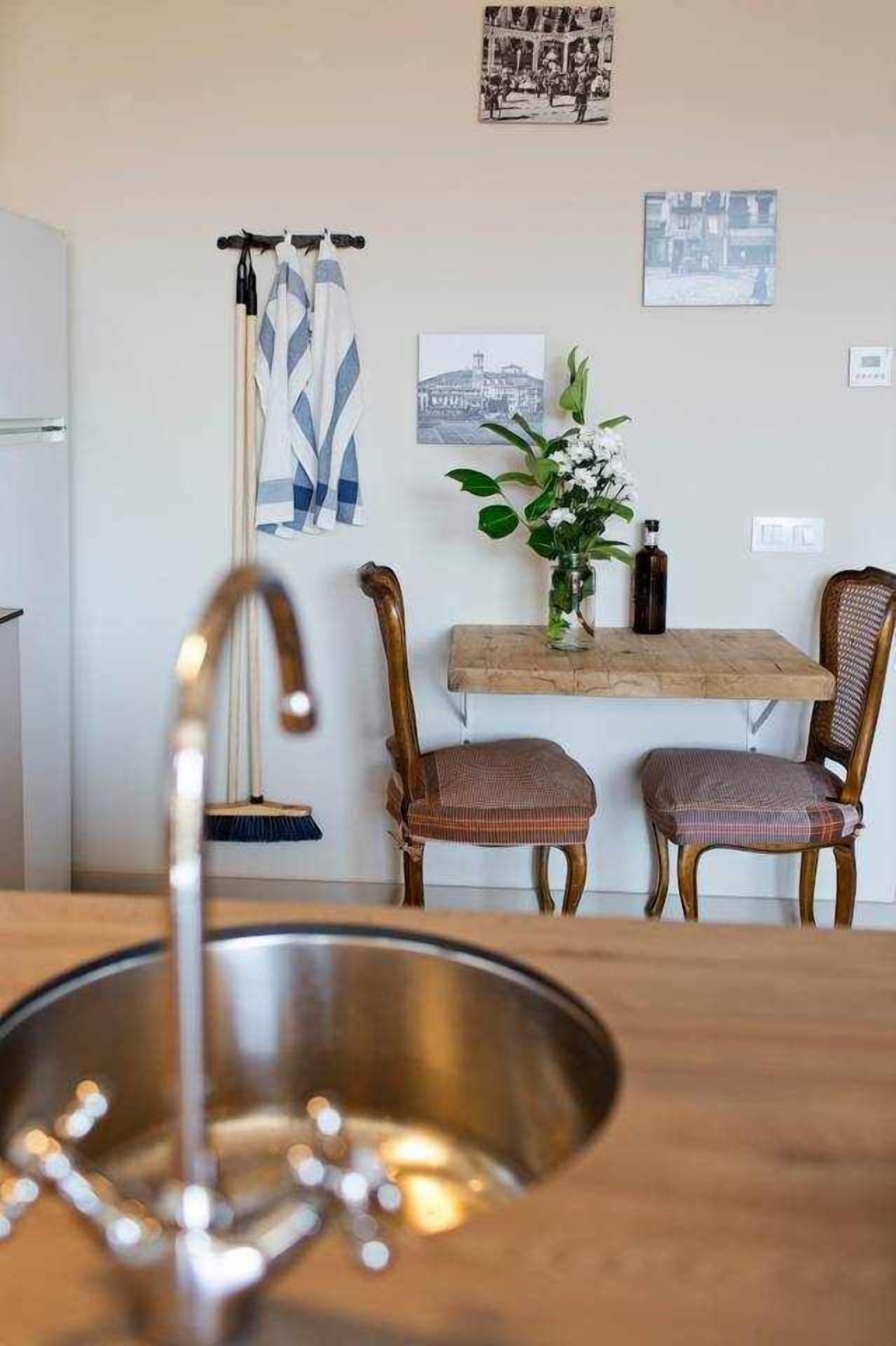 Une cuisine équipée d’un évier, de deux chaises, d’une table et d’un vase avec des fleurs.