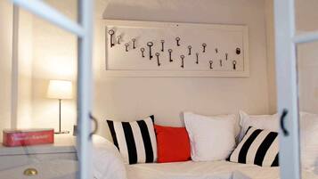 A bedroom with a bed, pillows, a nightstand, a lamp, and a wall-mounted key display.