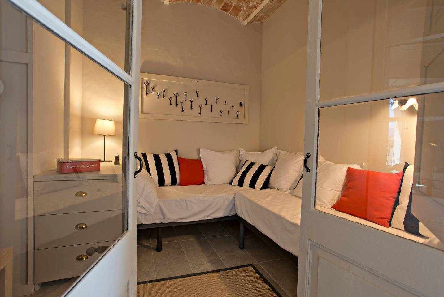 A corner bedroom with a bed, a nightstand, a lamp, and a wall-mounted key rack.