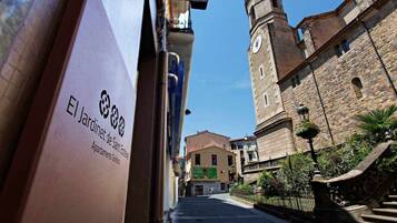 Vista de una calle con un edificio histórico que tiene una torre del reloj y un letrero que indica El Jardinet de Sant Esteve.