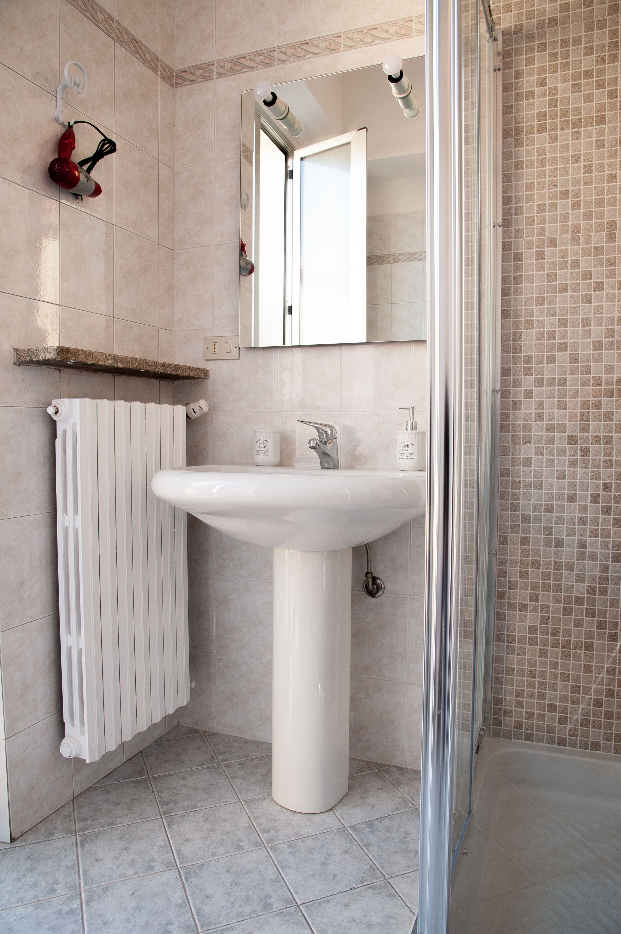 A bathroom with a white sink, a mirror, and a shower.