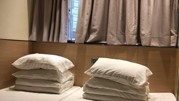 A hotel room with two beds, each with neatly folded white linens and pillows. - China Guest House (Kowloon)