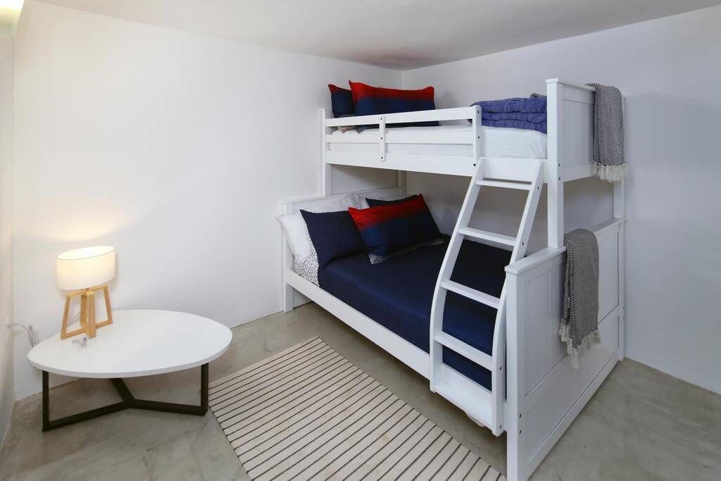 A bunk bed room with a round table and a lamp.