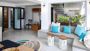 A modern living room with a grey sofa, blue cushions, and a coffee table. There are potted plants and a staircase in the background. - Villa Robalo - Villas del Palmar (Sayulita)
