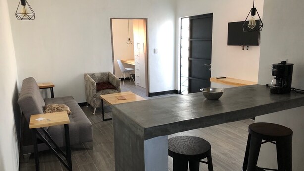 Une cuisine moderne dotée d’un îlot central, de tabourets de bar, d’un canapé et d’un coin repas.