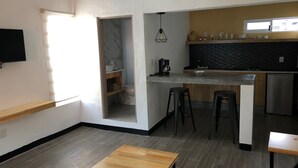 Une cuisine moderne avec un dosseret en marbre, des tabourets de bar en bois et un lave-vaisselle encastré.