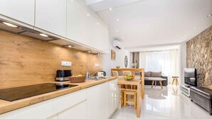 A modern kitchen with white cabinets, a wooden countertop, and a dining area with a table and chairs. - Holiday apartment with modern equipment (Vrbnik)