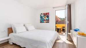 A modern bedroom with a large bed, a painting on the wall, and a balcony with outdoor seating. - Holiday apartment with modern equipment (Vrbnik)