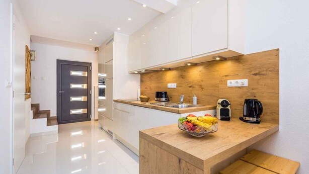 A modern kitchen with white cabinets, a wooden countertop, and a bowl of fruit. - Holiday apartment with modern equipment (Vrbnik)