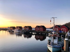 Un port avec des bâtiments rouges, une eau calme et des bateaux amarrés.
