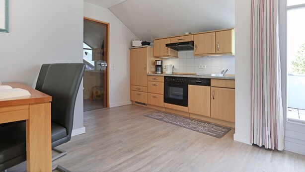A modern kitchen with wooden cabinets, a built-in oven, and a coffee maker.