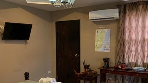 Hotellihuone, jossa on sänky, työpöytä, tuoli, televisio, ilmastointilaite ja kartta seinällä.