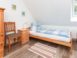 A bedroom with a wooden bed, a wooden chair, a nightstand, and a bedside table.