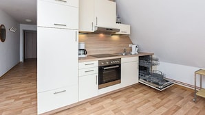 A compact kitchen with white cabinetry, a built-in oven, and a dishwasher.