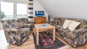 A living room with two patterned sofas, a wooden coffee table, and a television on a wooden cabinet.