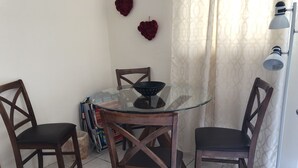 Un coin repas avec une table en verre entourée de chaises en bois, un lampadaire et des objets décoratifs accrochés au mur.