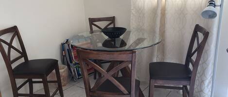 Un comedor con una mesa de vidrio rodeada de sillas de madera, una lámpara de pie y adornos en la pared.