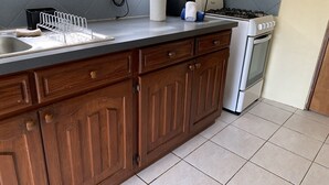 Une cuisine avec des meubles de rangement en bois, une cuisinière à gaz, un évier et un plan de travail.
