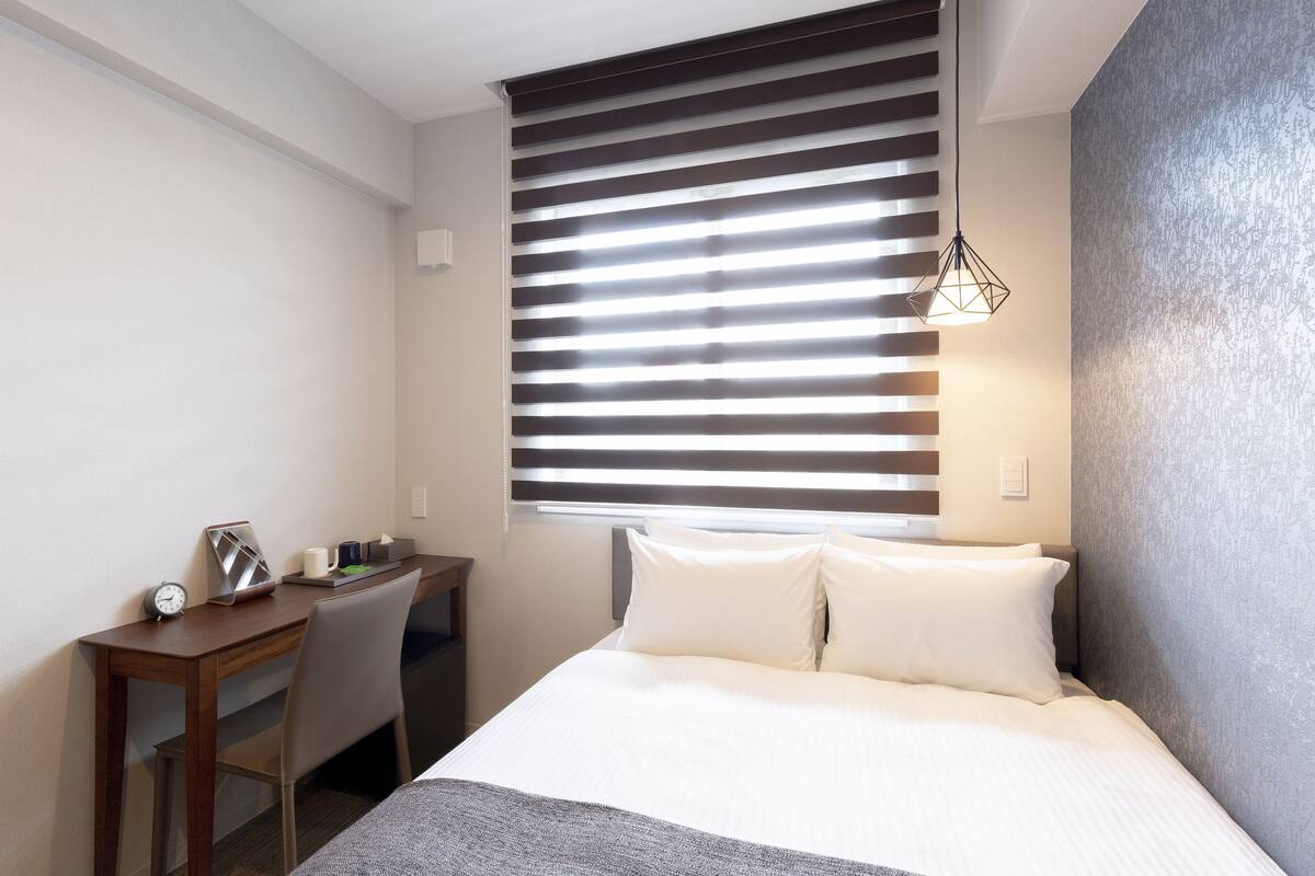 Ein Hotelzimmer mit Bett, Schreibtisch und Stuhl.