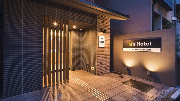 A modern hotel entrance with a tiled facade, a sign for 'M's Hotel', and a nameplate for 'GOJO NAGINATAGIRI'. - M’s Hotel Gojo Naginatagiri (Kyoto)