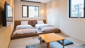 A modern hotel room with two beds, a wooden table, and tatami mats on the floor. - M’s Hotel Gojo Naginatagiri (Kyoto)