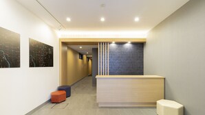 A modern reception area with a wooden reception desk, a blue accent wall, and a tiled floor. - M’s Hotel Gojo Naginatagiri (Kyoto)