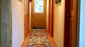 A hallway with a patterned carpet, wooden doors, and ceiling lights.