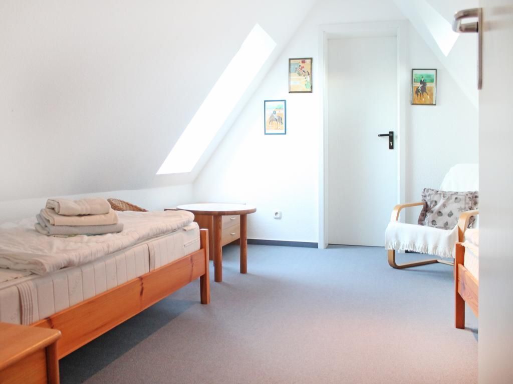 Una camera da letto con un letto, una sedia, un tavolino e una porta.