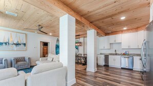 A spacious living area with a wooden ceiling, a dining area, and a kitchen with white cabinets and stainless steel appliances. - Seagrove, Amazing Gulf Views, Great Beach Access, Heated Pool, Pup Friendly
 (Santa Rosa Beach)
