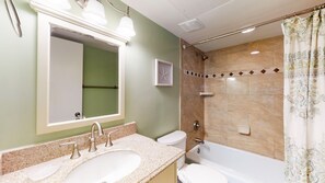 Et badeværelse med to vaske, toilet, badekar og bruser.