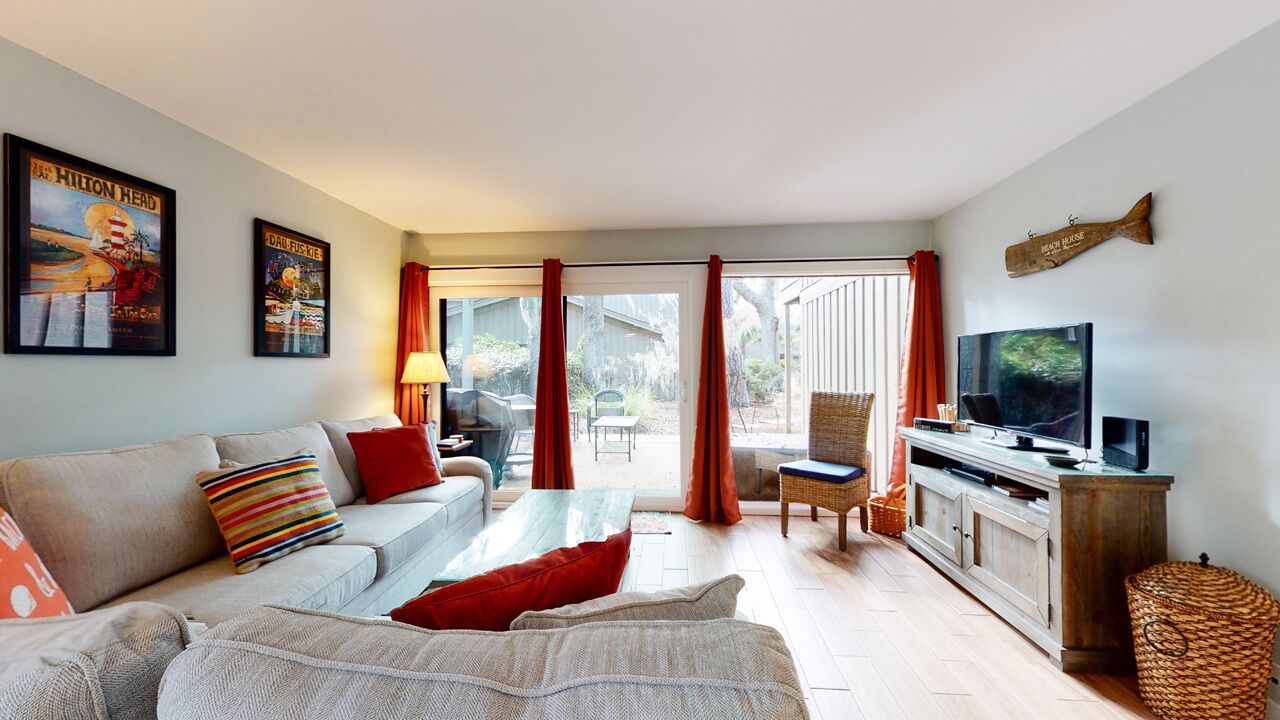 A living room with a sofa, a television, and a dining area with a table and chairs.