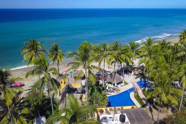 A resort with a pool, beach, and palm trees.