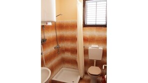 Een compacte badkamer met douche, toilet en wastafel.