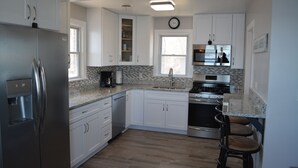 A modern kitchen with white cabinets, a stainless steel refrigerator, a built-in oven, and a microwave.