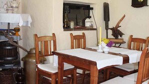 A dining area with a wooden table and chairs, a stove, and various kitchen items on the wall.