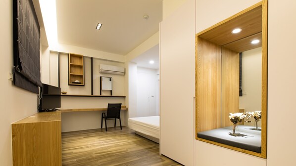A modern bedroom with a wooden desk, a chair, a bed, and a large mirror.
