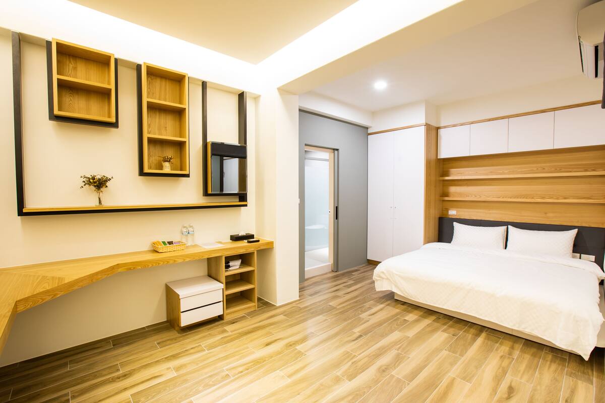 Un dormitorio moderno con un escritorio de madera, una cama y estanterías empotradas.