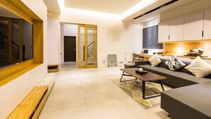 A modern living room with a sofa, coffee table, and a kitchen area in the background. - Araucaria Residence (Huxi)